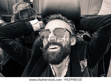 Fashion portrait of young bearded man ready for road trip - Cheerful hipster guy sitting in car looking the sky - Black and white editing - Warm vintage retro filter