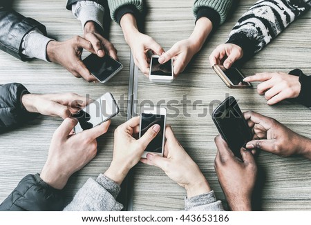Group of friends having fun together with smartphones - Closeup of hands social networking with mobile phones - Technology and phone addiction concept - Main focus on bottom hands - Vintage filter