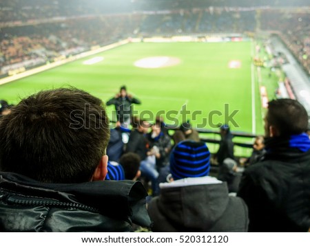 Soccer fans celebrate their team in football italian stadium - People watching sport match singing and screaming - Love for sport concept - Soft focus on man head jacket - Warm filter