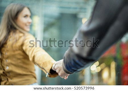 Young woman hat holding man by hand in city urban center - Boyfriend following beloved girlfriend during holidays honeymoon - Love and tender moments concept - Focus on man hand - Warm vintage filter