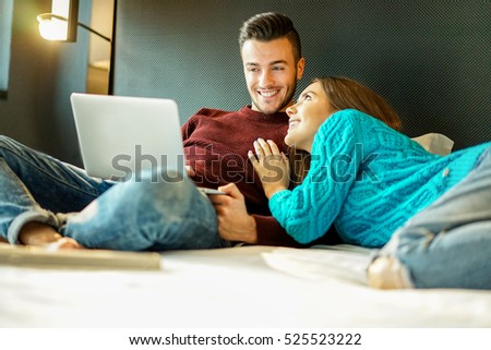 Happy boyfriend and girlfriend doing shopping online with laptop computer - Young people having fun buying presents in internet at home - Holidays and shopping concept - Focus on man - Warm filter
