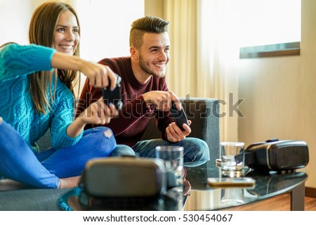 Happy friends playing video games with virtual reality glasses - Young people having fun with new technology console online - Happiness and gaming concept - Focus on man face - Warm filter