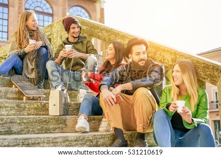 Happy friends toasting coffee take away and listening music from vintage stereo - Young people having fun in city university center - Study and friendship concept - Warm filter - Focus on left guys