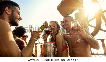 Happy friends making boat party outdoor with sangria and champagne - Young people toasting wine and celebrating summer vacation - Friendship concept - Focus on two right guys - Warm filter