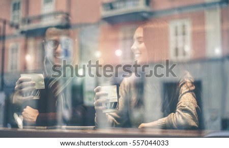 Happy friends toasting coffee in street city bar - People having a break sitting in cafe  drinking cappuccino - Reflection view from outside - Focus on woman right hand - Matte warm filter