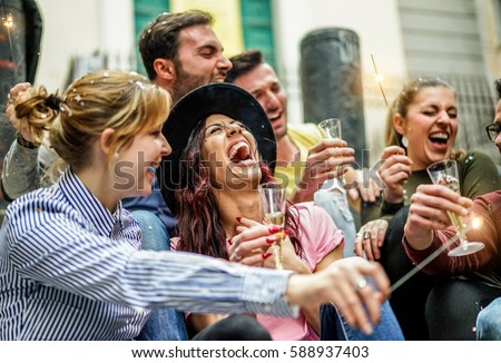 Loud happy friends making party with champagne,confetti and sparklers outdoor - Young people celebrating birthday drinking and laughing - Fest concept - Focus on center girl with hat - Unfiltered