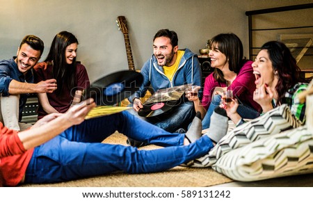 Happy friends having party listening vintage vinyl disc albums at home - Young people having fun drinking shots and laughing together - Warm contrast filter