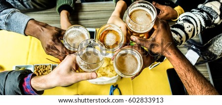 Top view of friends cheering with home brew in pub bar restaurant - Young people hands toasting and beers half pint - Party concept - Warm filter - Focus on bottom hands glasses