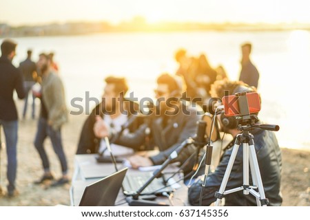 Group of young people making a video feed from beach party at sunset - Man vlogger using mobile phone camera for filming festival event - New technology trends concept - Focus on smartphone