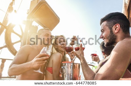 Happy friends having boat party outdoor with sangria and champagne  - Young people toasting wine in exclusive rich summer vacation  around europe - Travel ,friendship concept - Main focus on right man