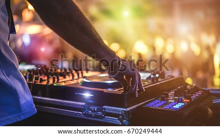 Dj mixing outdoor at beach party festival with crowd of people in background - Summer nightlife view of disco club outside - Soft focus on hand - Fun ,youth,entertainment and fest concept