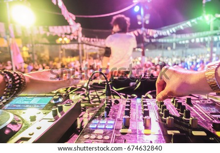 Dj mixing outdoor at beach party festival outdoor with crowd of people in background - Soft focus on center right hand - Fun, summer, youth, nightlife, music and entertainment concept - Retro filter