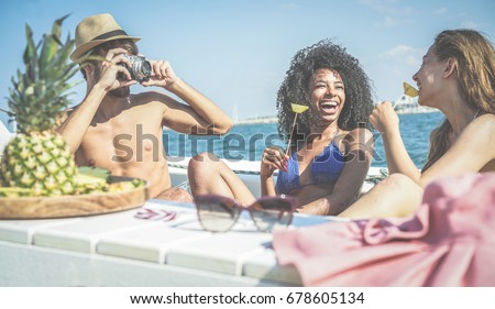 Happy friends having fun and eating fresh pineapple fruit at boat party - Young people taking photos in caribbean sea tour - Youth, tropical, travel and summer vacation concept - Focus on black girl