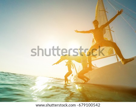 Crazy friends jumping off the boat into the ocean - Young happy people having fun diving into the sea - Travel, tropical, summer and concept - Soft focus on left man face - Tilted horizon composition