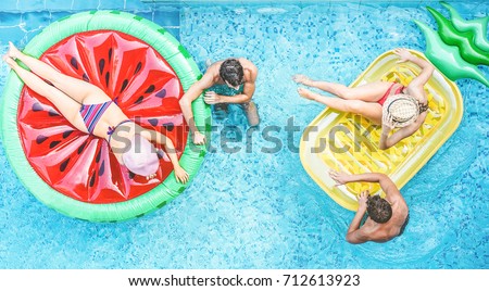 Happy friends having fun inside swimming pool - Young people enjoying summer holidays vacation in tropical hotel resort - Travel,holidays,youth and friendship concept - Warm filter