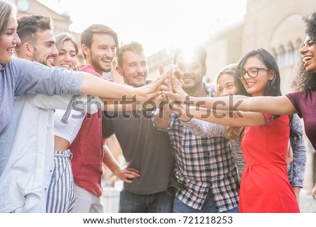 Young students stacking hands outdoor in college campus - Happy people celebrating together - Youth, university, relationship and friendship concept - Focus on hands - Original light color tones
