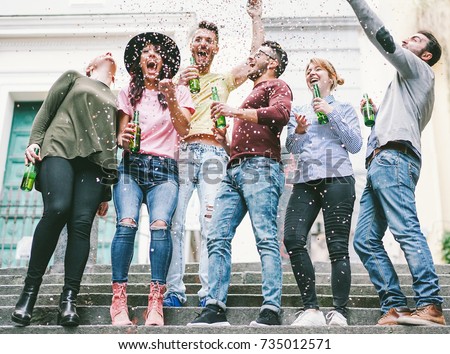 Happy crazy friends celebrating on the street drinking beer and throwing confetti - Young students having fun together - Friendship and youth concept - Vsco warm filter - Main focus on center guys