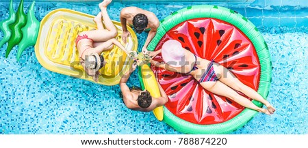 Happy friends having cheering with cocktails in swimming pool party - Young people enjoying summer holidays vacation in tropical hotel resort - Travel, holidays, youth and friendship concept