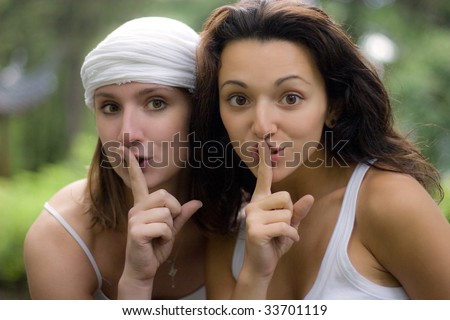 Two girls, having put a finger to lips, a sign show that they will not tell a secret and ask it nobody to tell