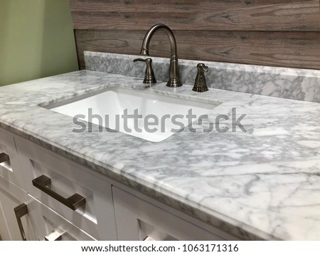 Bathroom marble countertop with white sink, chrome faucet and white cabinets