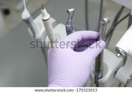 Hand of dentist holding dental drill machine with turbine