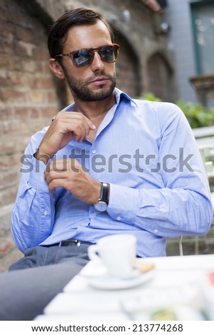 Young fashion man with beard drinking espresso coffee in the city cafe