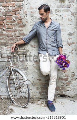 Casual young man stands with his back against a brick wall