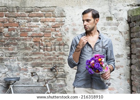 Casual young man stands with his back against a brick wall