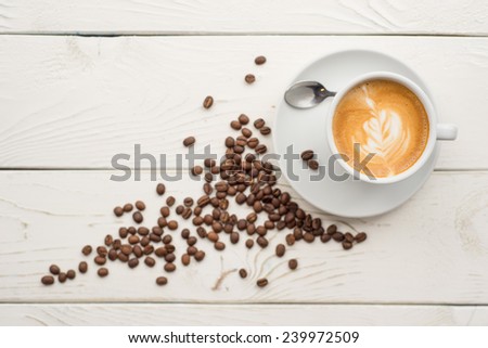 Cup of coffee on vintage table with coffee beans and milk