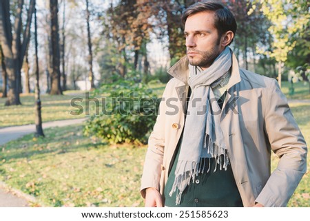 Handsome man wearing trench coat in park, retro vintage style filtered on