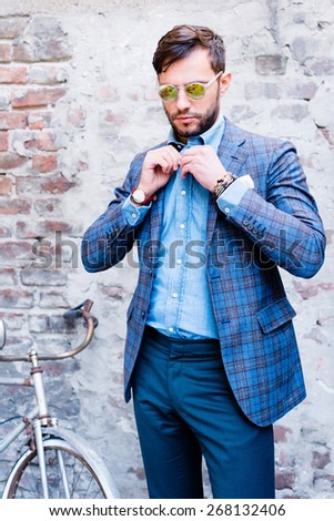 Handsome man with glasses ina suit, against old vintage wall, outdoors.