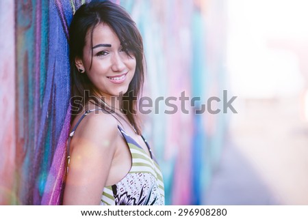 Beautiful urban girl in front of graffiti wall, fake lens flare