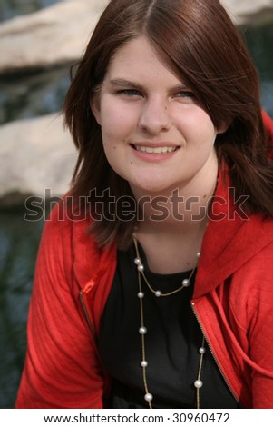 Smiling girl sitting by a rocky stream