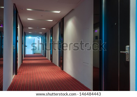 modern hotel corridor with red brown capet to exit stairway.