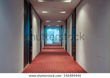 modern hotel corridor with red brown capet to exit stairway.