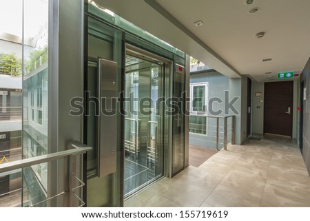 Apartment Interior With Walkway And Glass Lift Opened.
