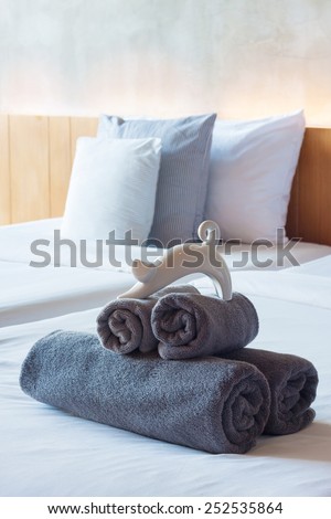 Towels roll on bed in modern hotel room.