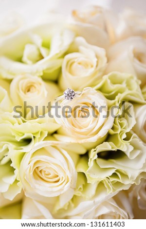 A diamond ring lies on a bouquet