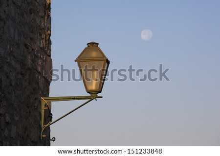 Street lamp on a stone wall, with full moon in the sky