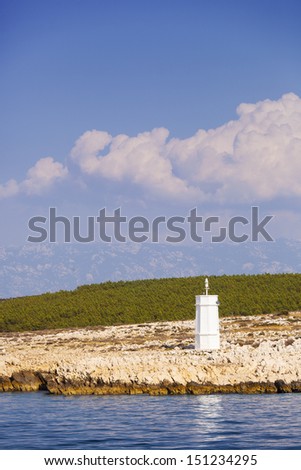 Solitary light beacon on island Rab, with distant view on mountain Velebit
