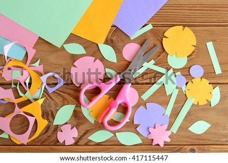Paper flowers, paper sheets, scissors, paper scrap on a wooden table. Paper flower craft for kids. Children\'s art project.