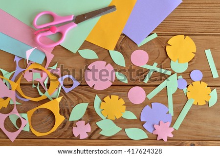 Paper flowers, paper sheets, scissors, paper scrap on a wooden table. Paper flower craft for kids. Children\'s art project.