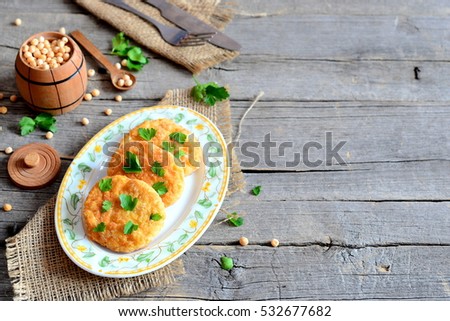 Roasted pea cutlets on a plate. Healthy diet cutlets cooked from yellow dried peas and decorated with parsley. Fork, knife on an old wooden background with copy space for text. Diet food idea. Closeup