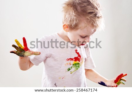 The baby boy with gouache soiled hands and shirt isolated on the white background