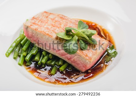 cooked fish in a plate decorated with verdure