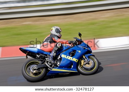 Motor biker on a race circuit speeding round a corner with a race circuit kerb behind