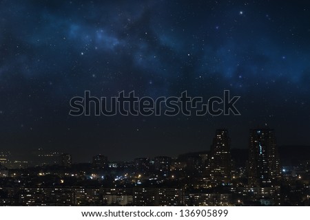 City landscape at nigh with sky filled with stars, nebula and galaxy