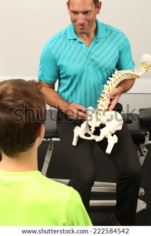 A Chiropractor showing a model of the human spine to a boy