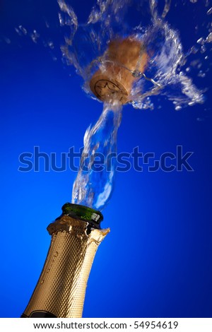 closeup of an uncorked champagne bottle with cork flying away on the liquid