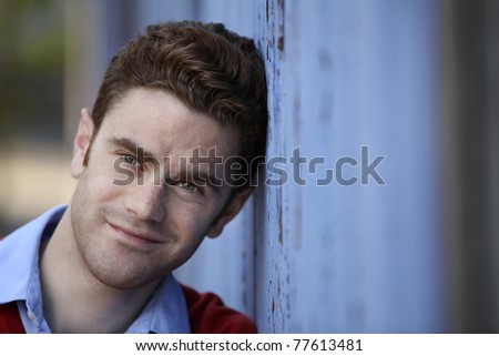portrait of a young man leaning on a blue wooden wall